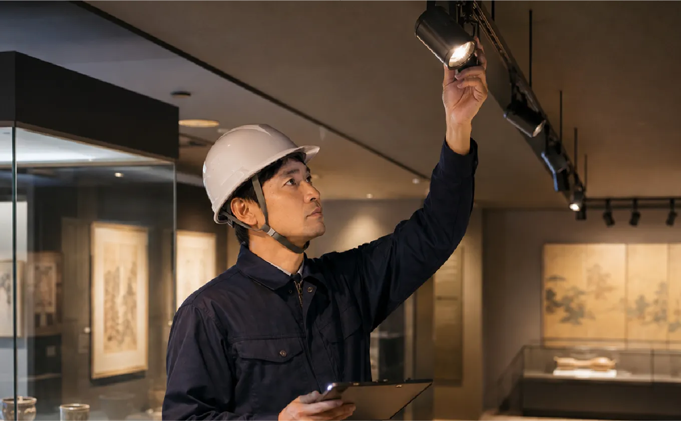 美術館の展示室で照明調整を行うKAMEDENのスタッフ